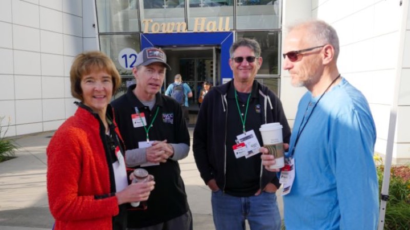 Four volunteers with lanyards and coffee outside the Town Hall entrance.